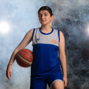 a woman in a blue and white uniform holding a basketball