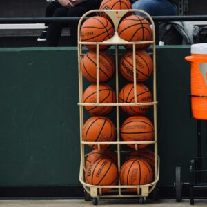 A man sitting on a bench next to a rack of basketballs